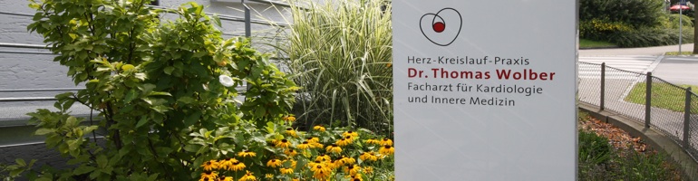Praxisstele mit Logo vor dem Gebäude